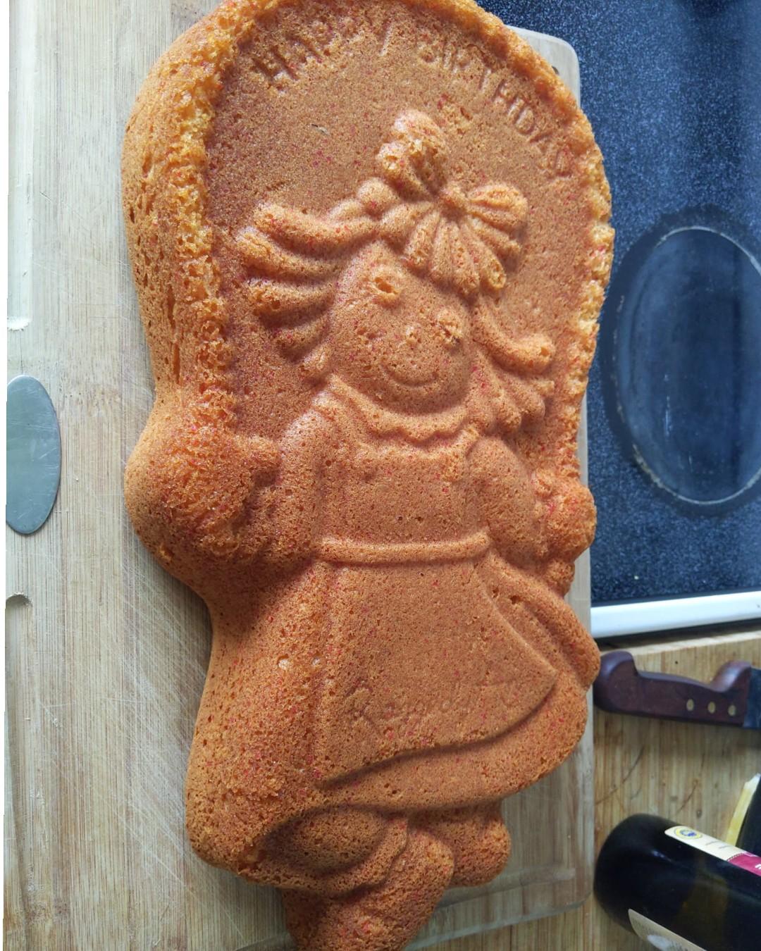 An un-iced cake showing an image of Raggedy Ann skipping with a jump rope.