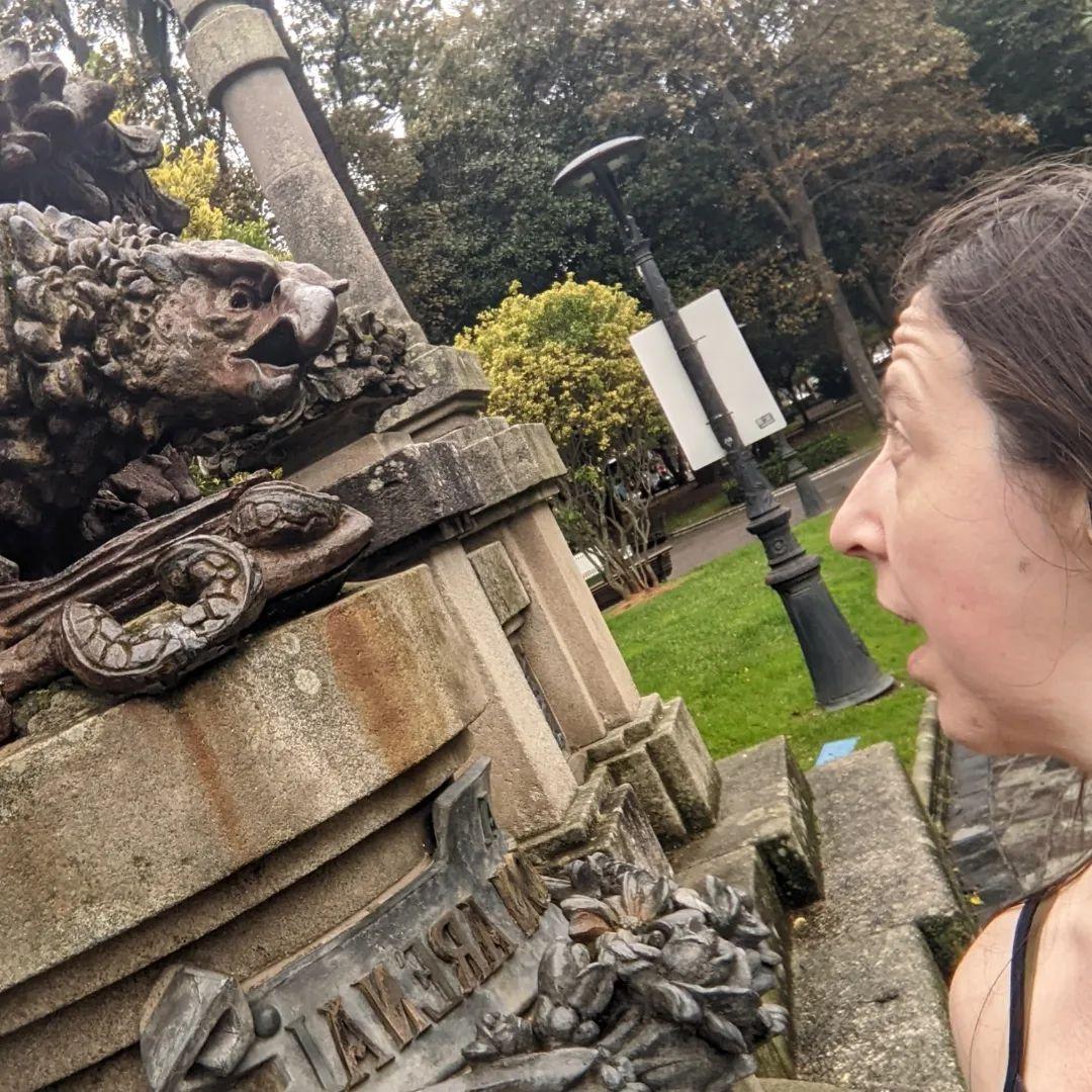 A white woman looking back at an eagle statue.  Both woman and statue have their mouths open.