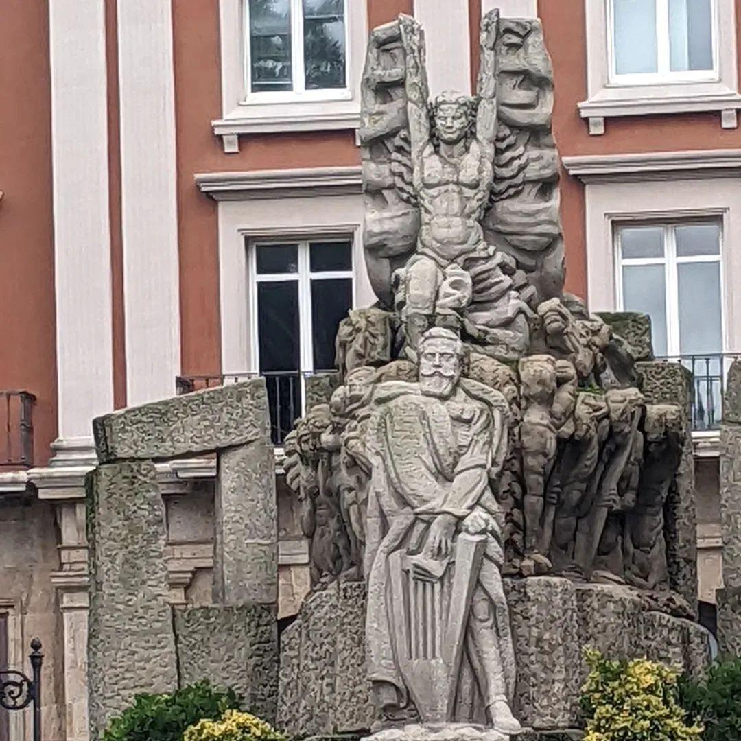 A stone monument of a dude with a harp underneath some sort of winged being.